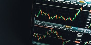 A close-up of a computer screen displaying two financial charts with candlestick graphs and numerical data, showing fluctuating prices in a trading platform interface, ideal for analyzing the Best Forex Signals. | ZIIMP
