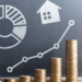 A bar graph made of stacked coins increases in height from left to right in front of a chalkboard. The chalkboard displays icons representing personal finance like a pie chart, house, magnifying glass, shopping cart, and piggy bank, along with a line graph showing an upward trend. A calculator is on the left. | ZIIMP